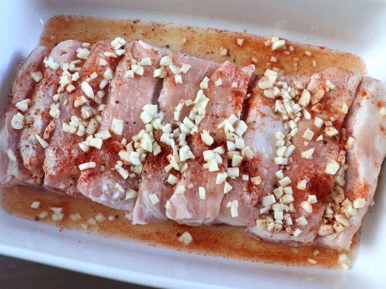 Côtes de porc sur un plat de cuisson assaisonné de sel, poivre, paprika, ail haché et jus de citron