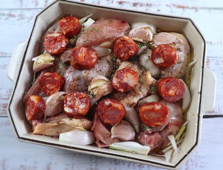 Poulet, chouriço, oignon, ail, huile d'olive, poivre, muscade et romarin sur un plat allant au four
