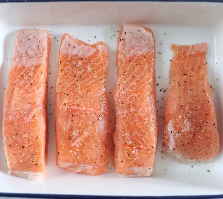 Assaisonner les filets de saumon avec du sel et du poivre sur un plat allant au four